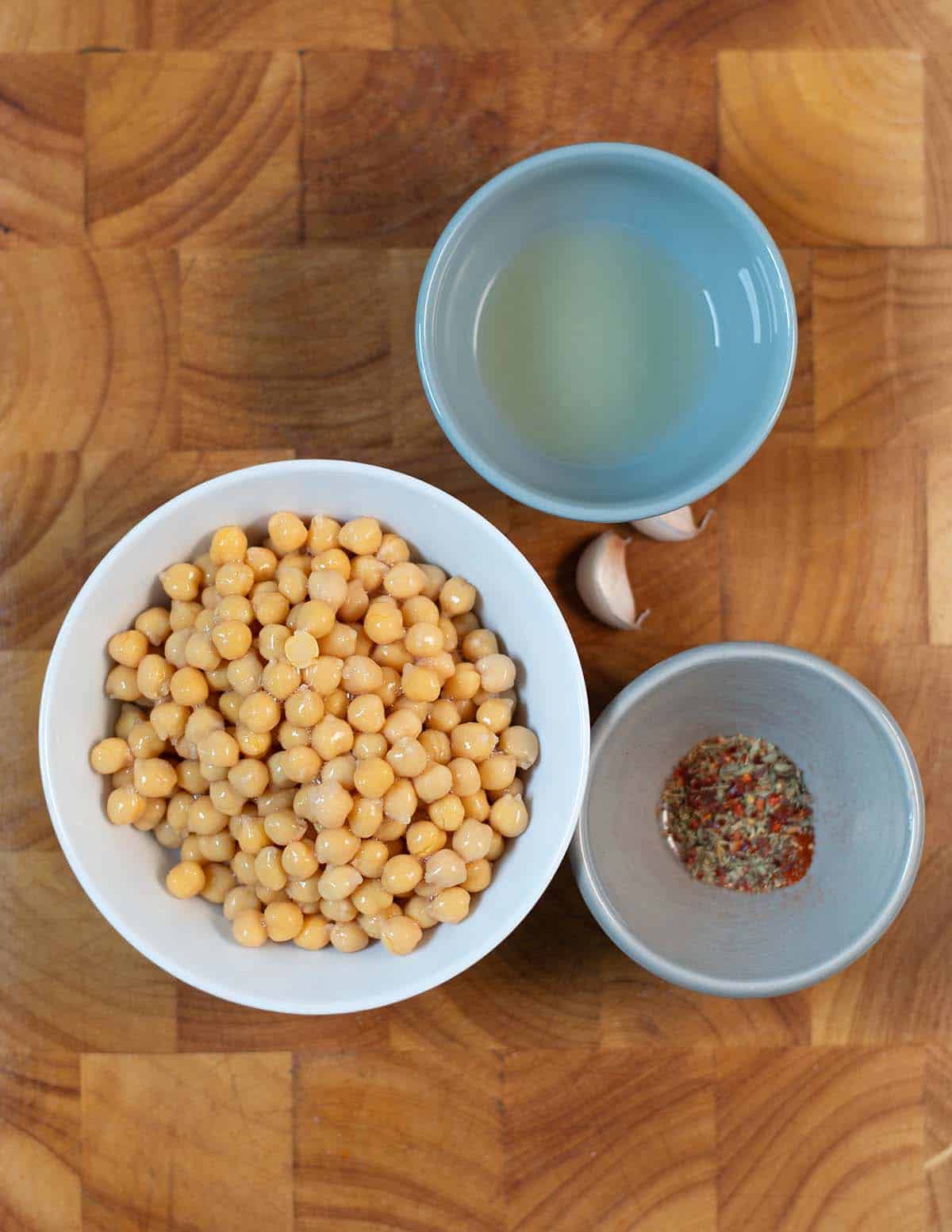 Ingredients needed to make Marinated Chickpeas on a wooden cutting board.