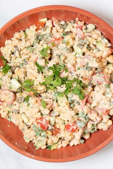 Serving of Smashed Chickpea Salad on a plate, garnished with parsley.