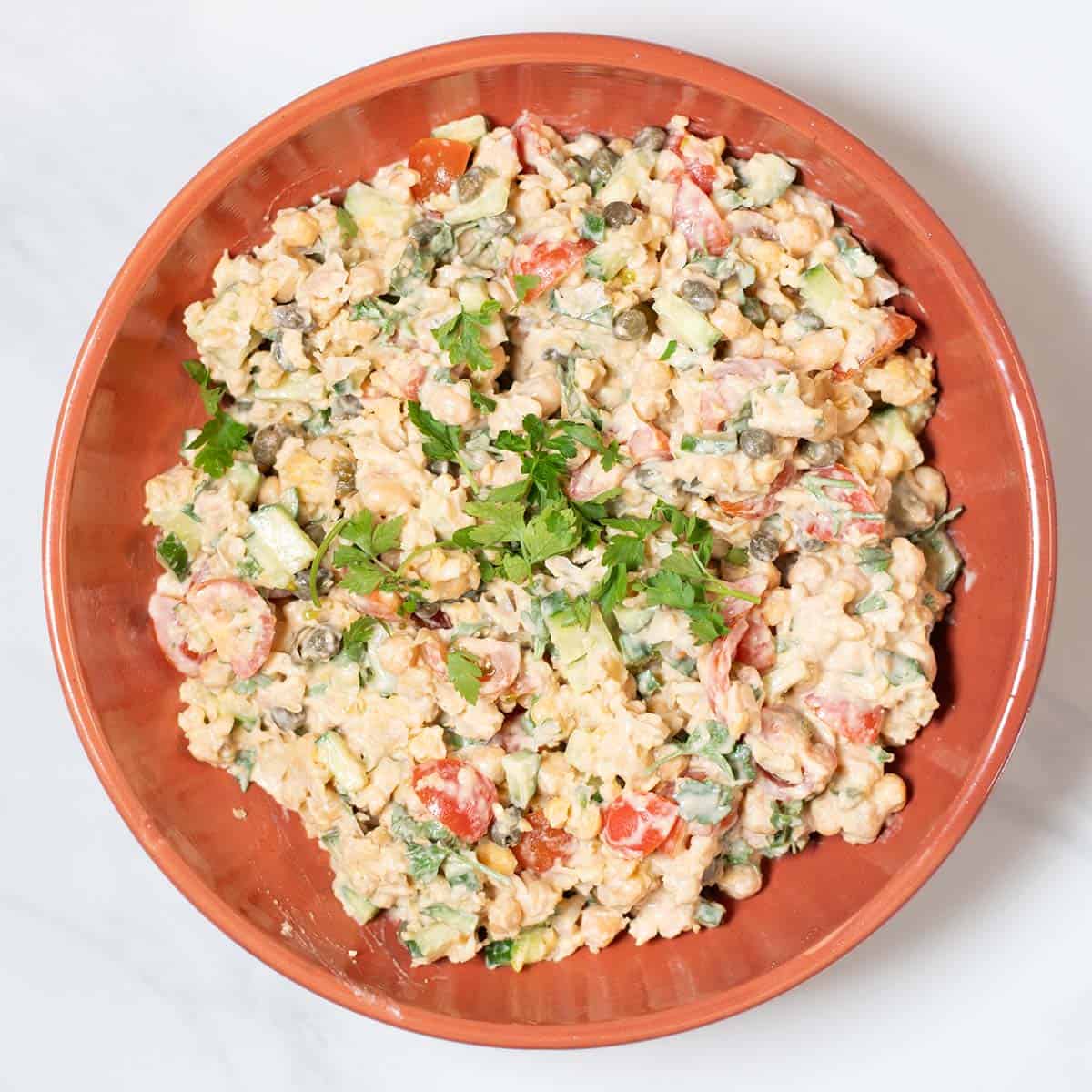 Serving of Smashed Chickpea Salad on a plate, garnished with parsley.