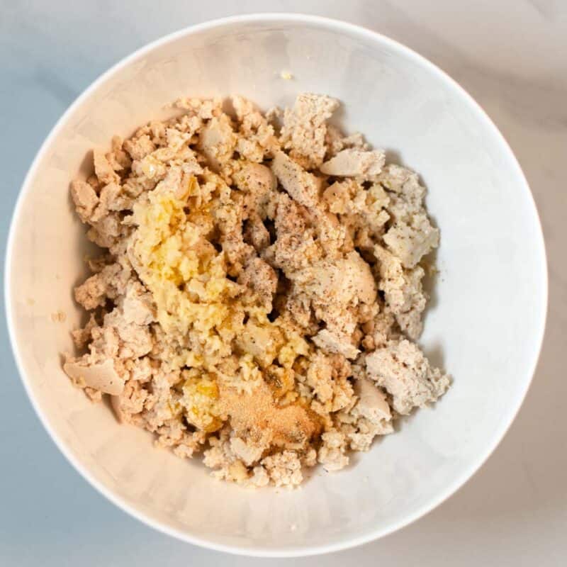 Cumbled tofu, spices, and olive oil in a mixing bowl.