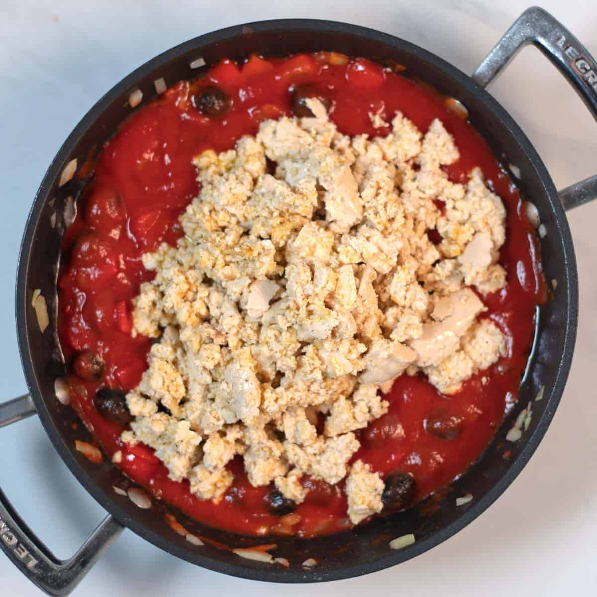 The marinated tofu is added to the tomato sauce.
