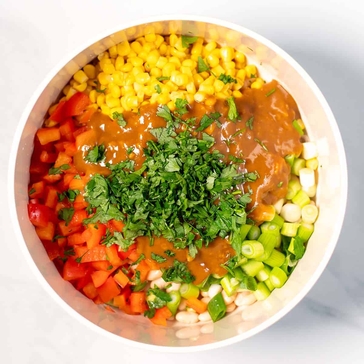 Dressing and fresh parsley are added to the bowl with the salad ingredients.