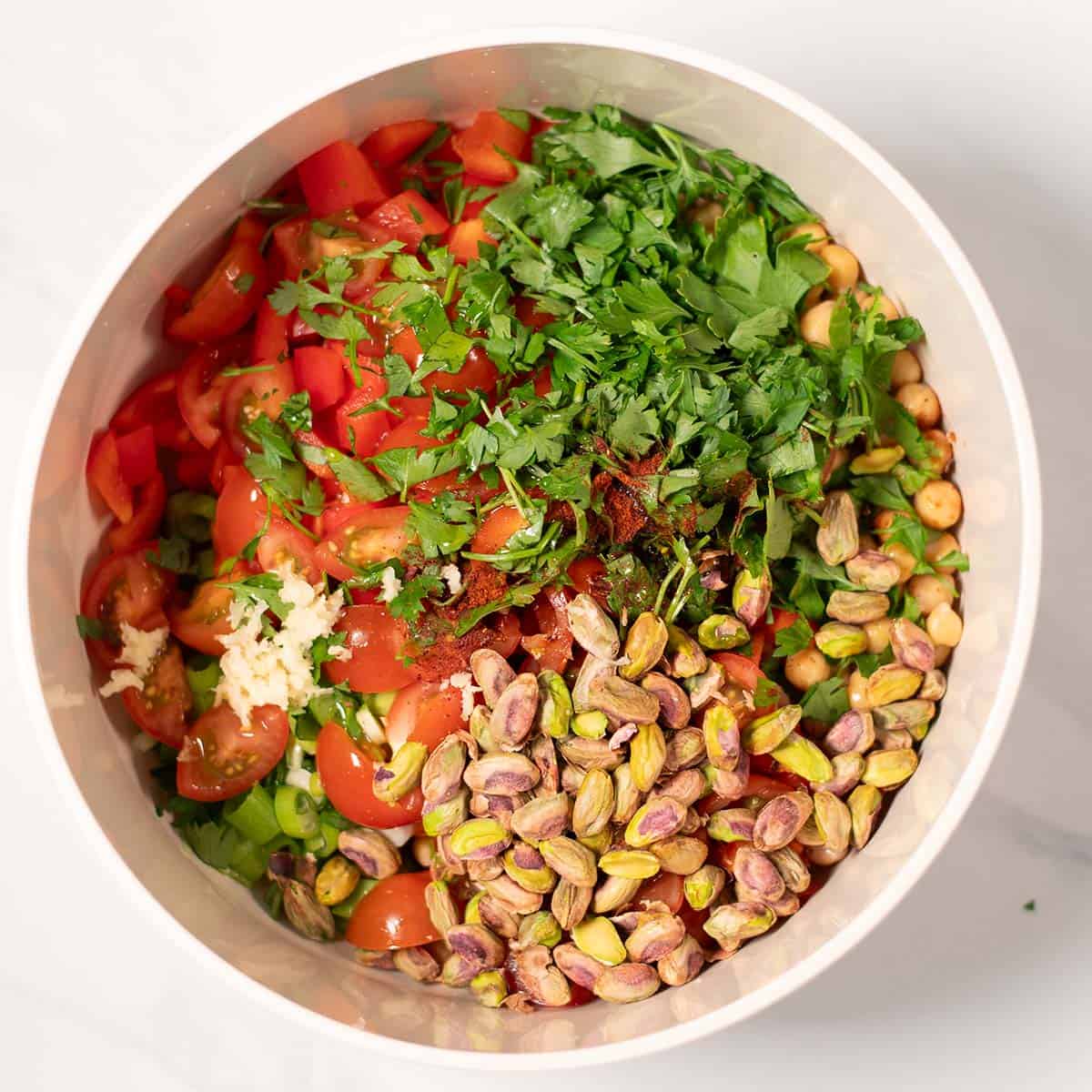 Pistachios and dressing ingredients are given to the mixing bowl.