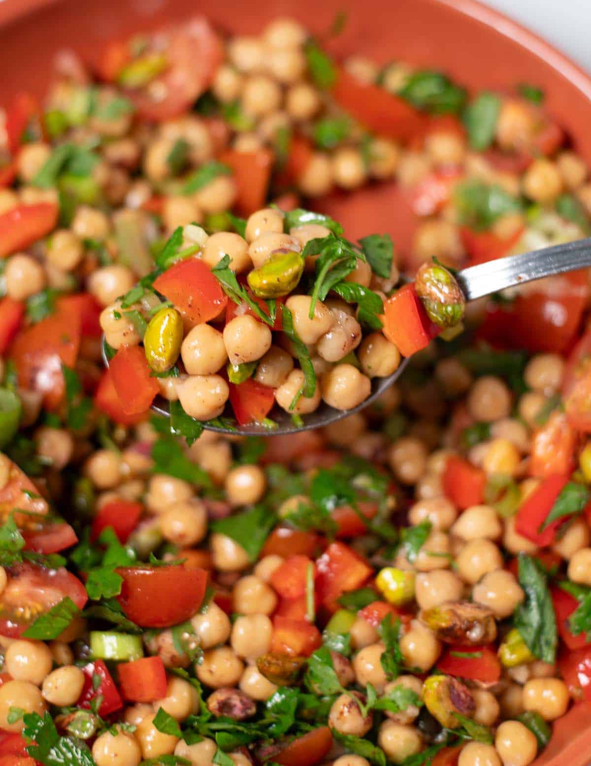 A spponful of Balela Salad is lifted from the serving plate.