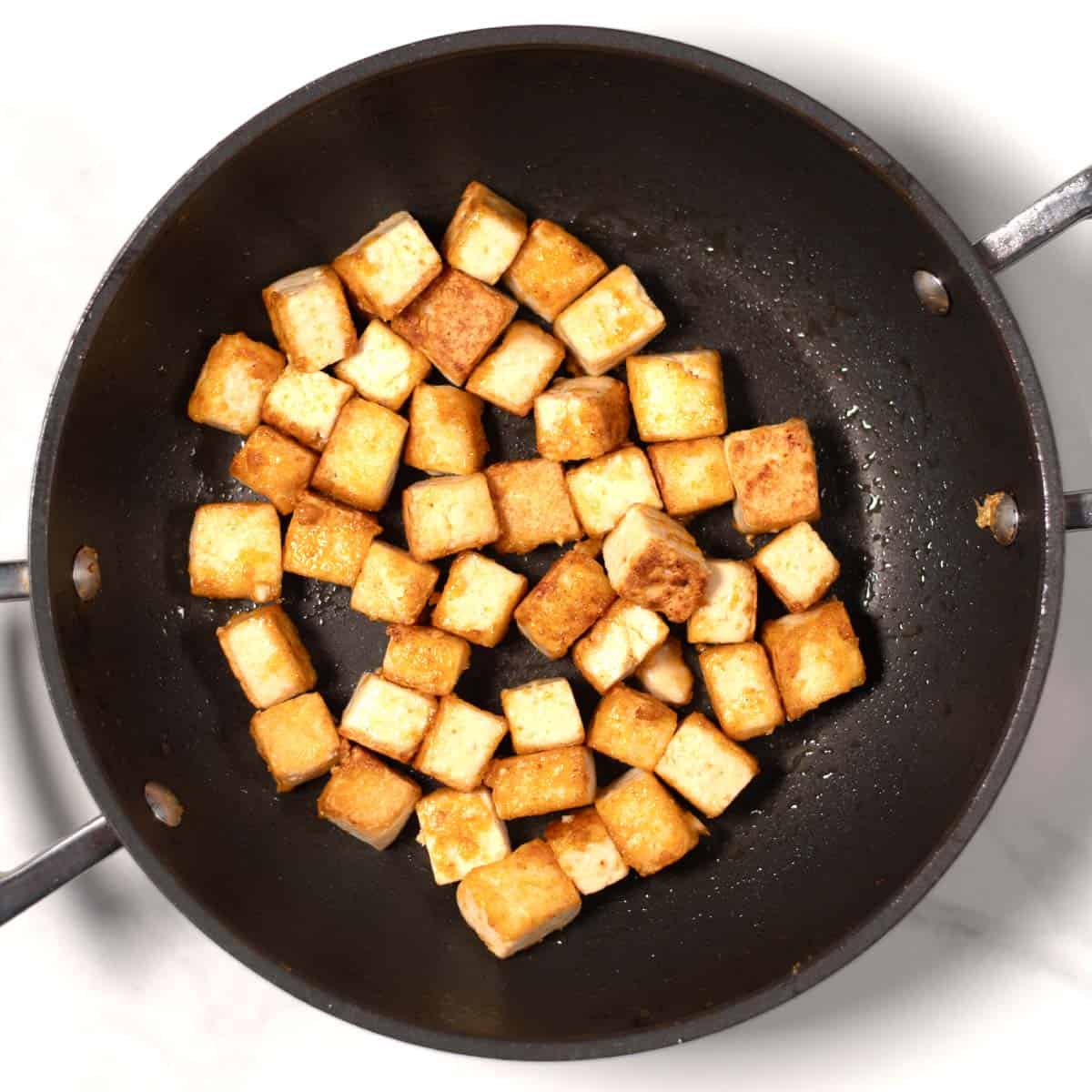 Crispy roasted tofu cubes in a pan.