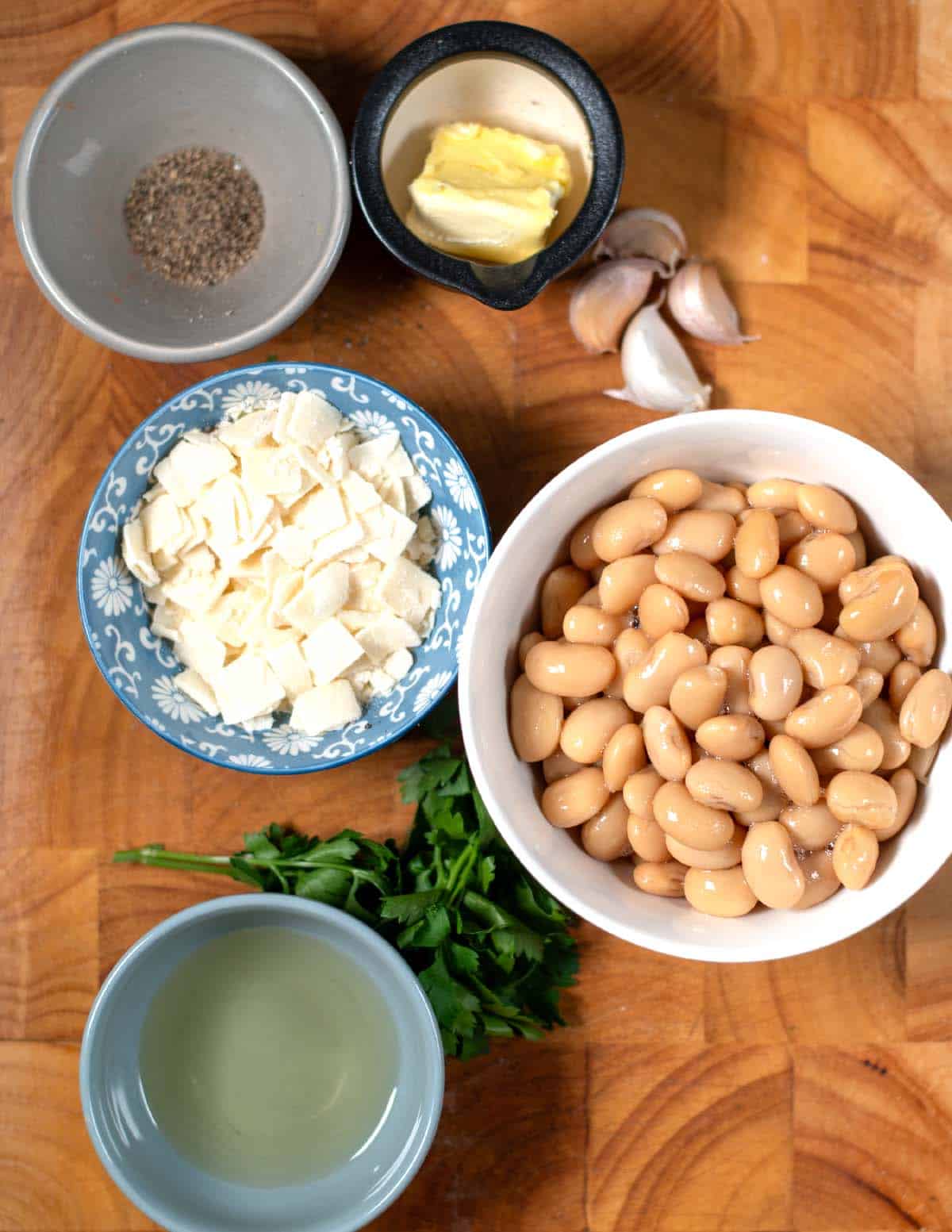 Ingredients needed to make Caco e Pepe Beans collected on a cutting board.