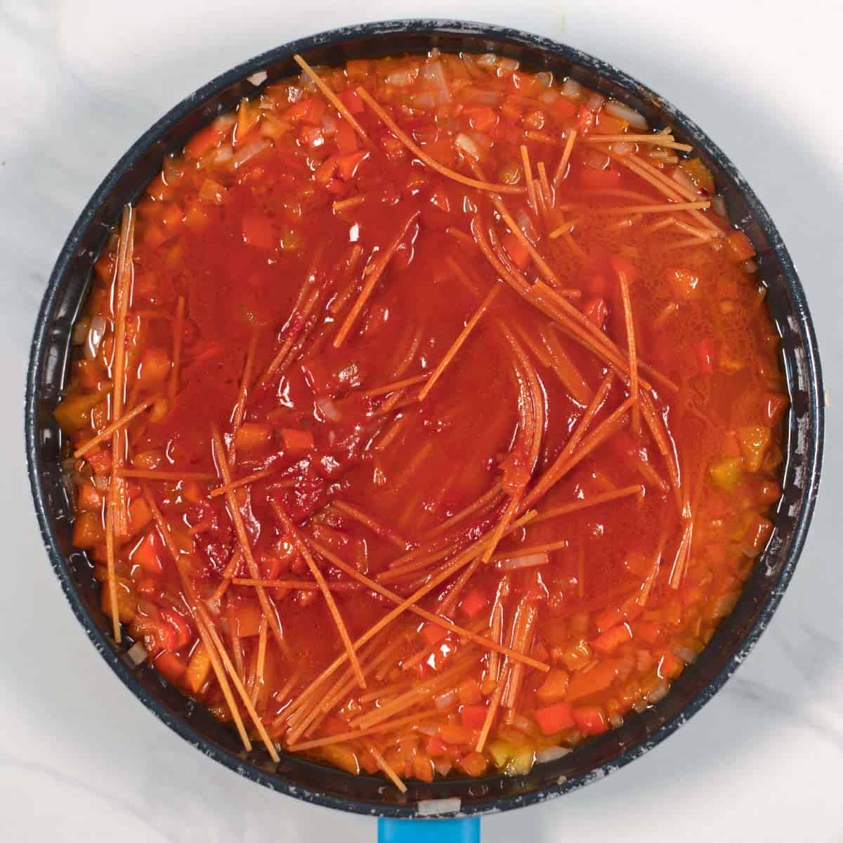 View of a pan in which the pasta is cooking in the sauce.