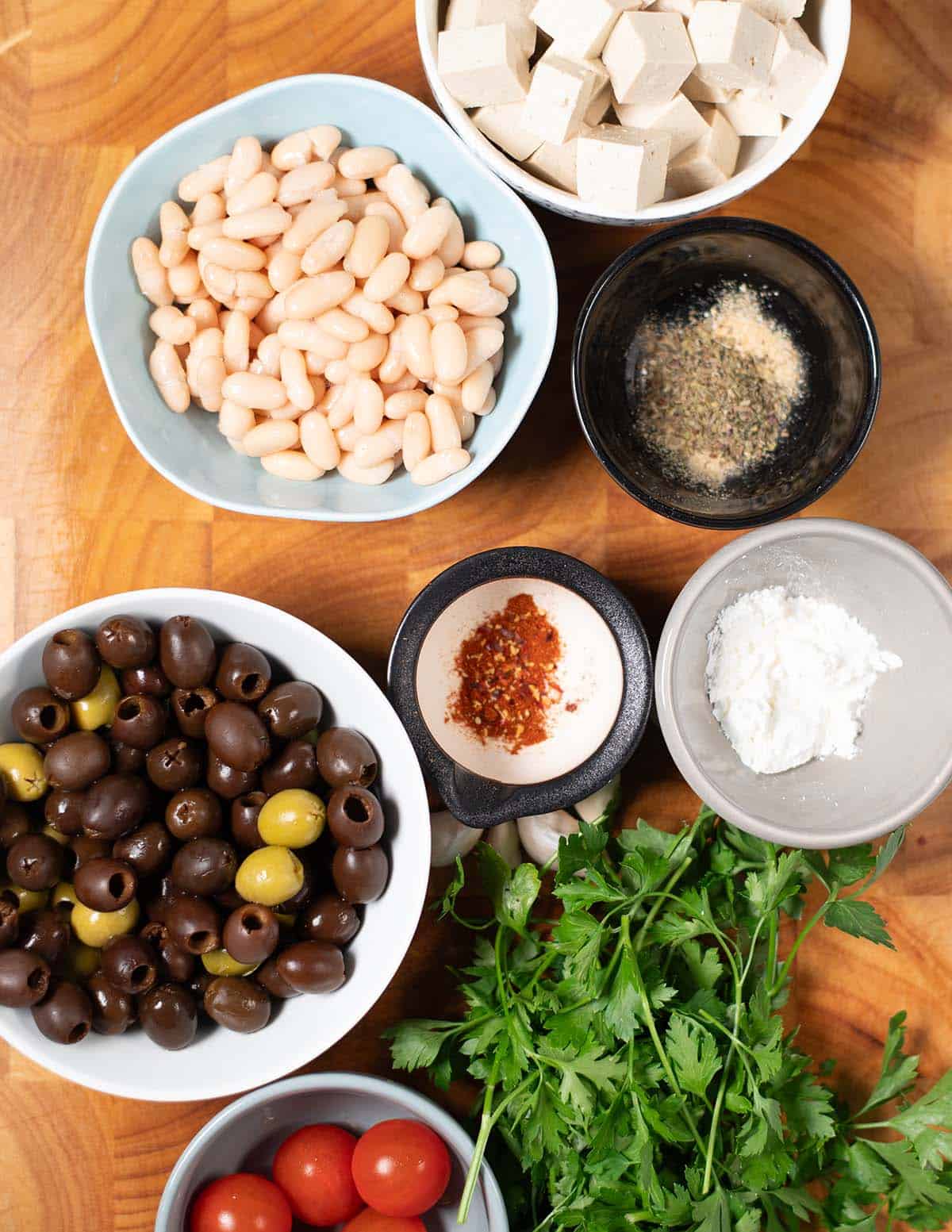 Ingredients needed to make Olive Salad are collected on a wooden board.