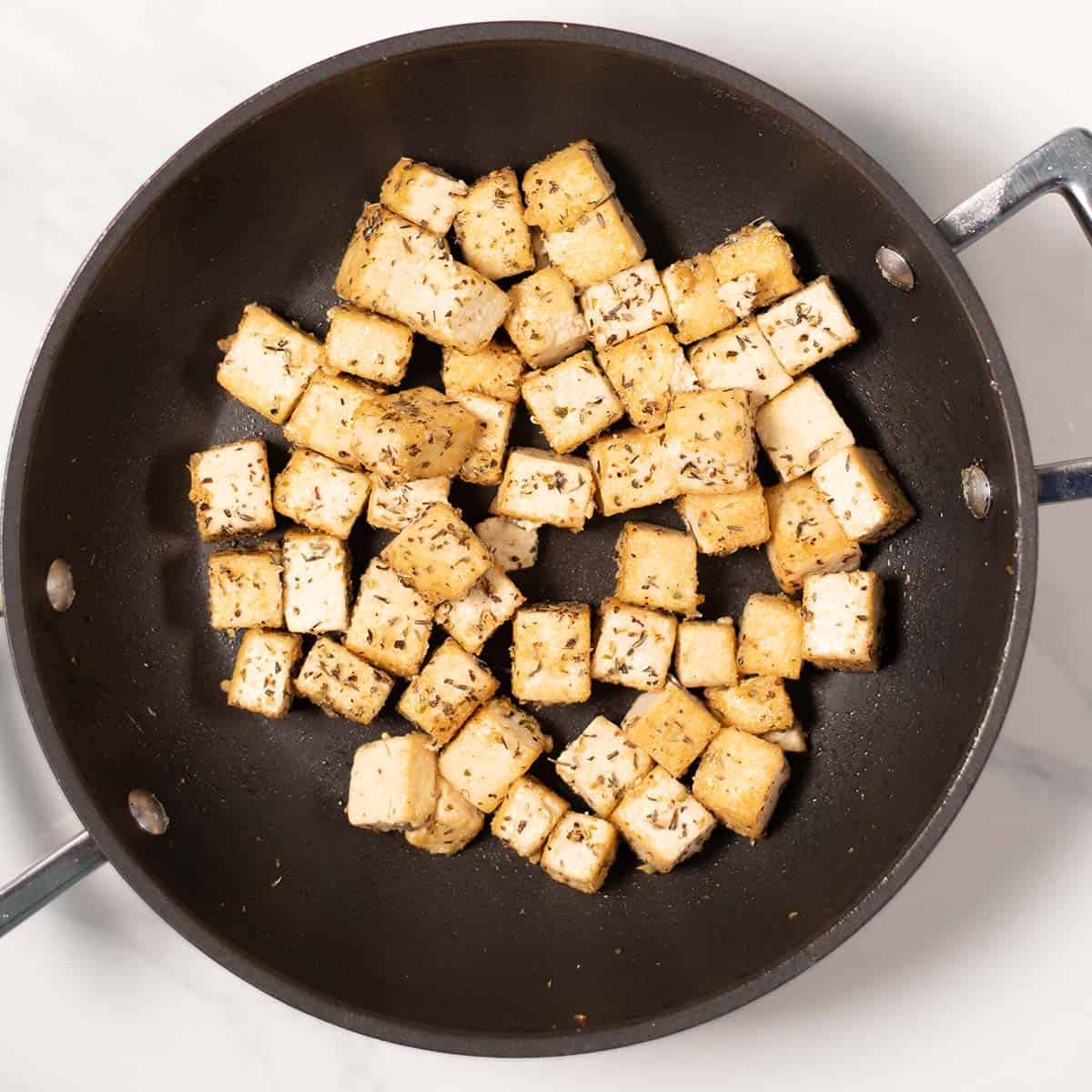 Tofu is fried cripsy in a pan.