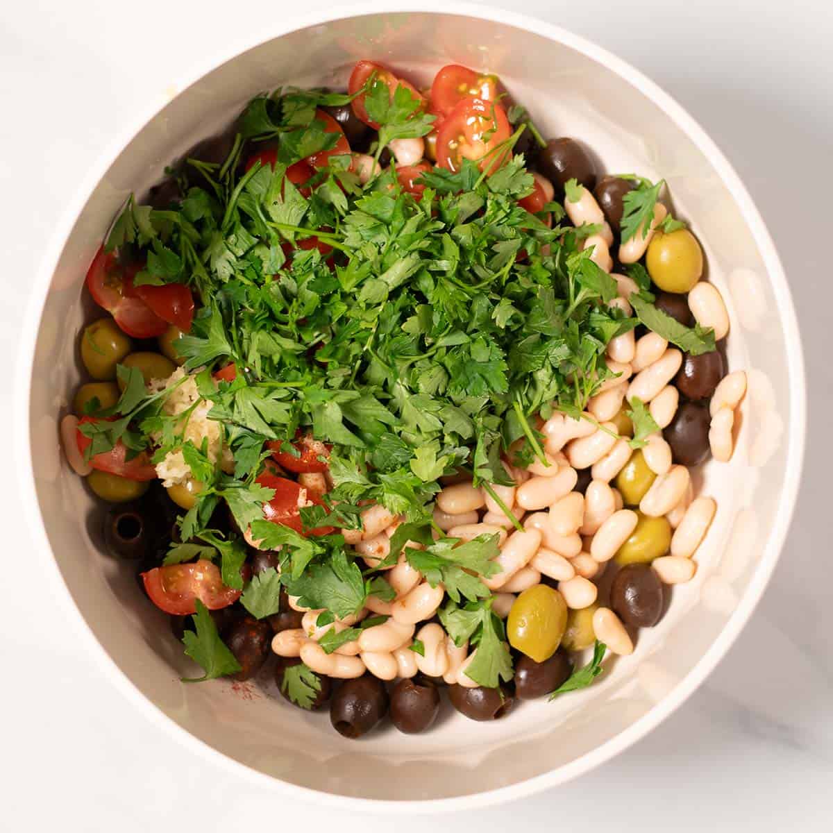Salad ingredients are given to a large mixing bowl.
