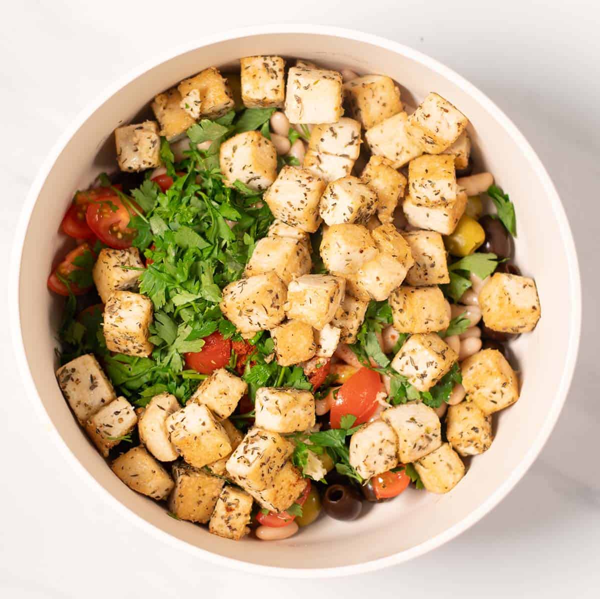 Crispy tofu is added to the salad mixing bow.