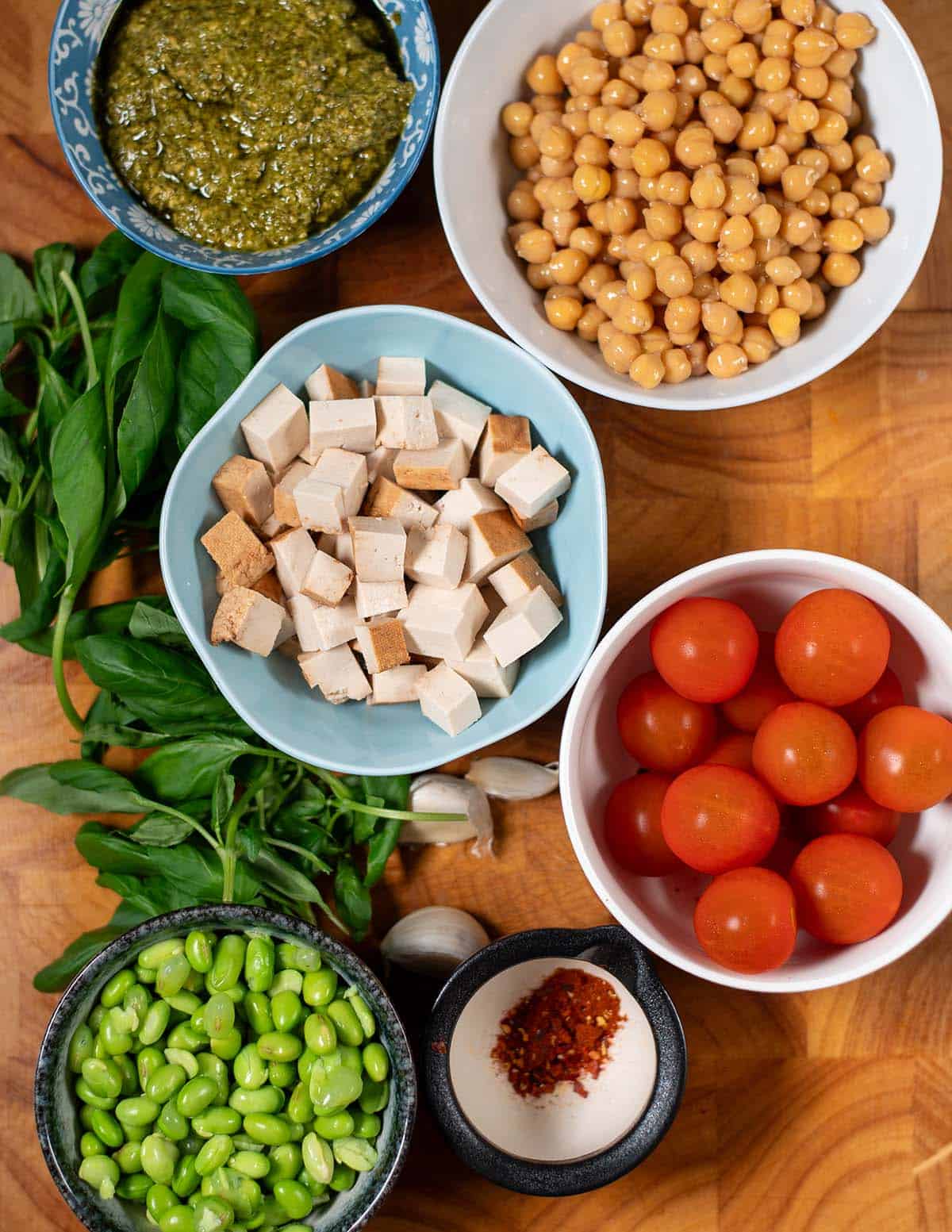 Ingredients needed to make Pesto Chickpeas are collected on a cutting board.