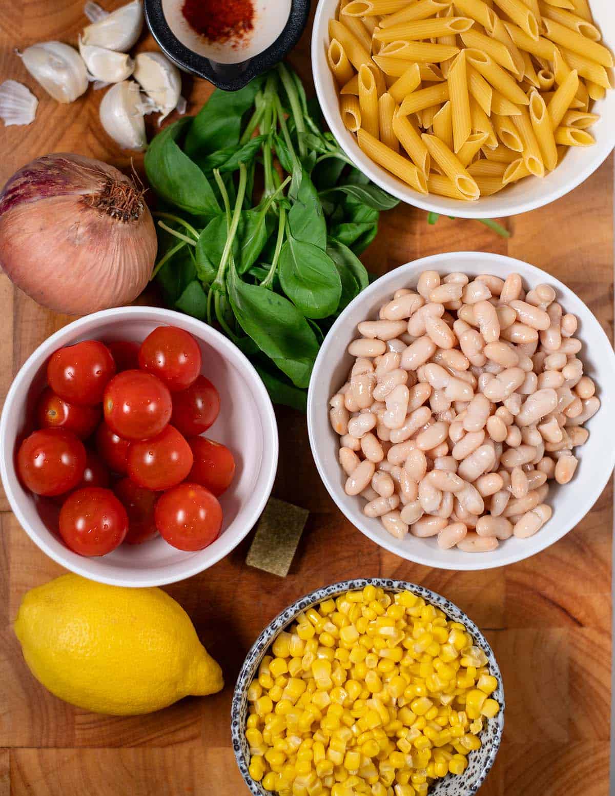 Ingredients needed to make Corn Pasta are collected on a wooden board.