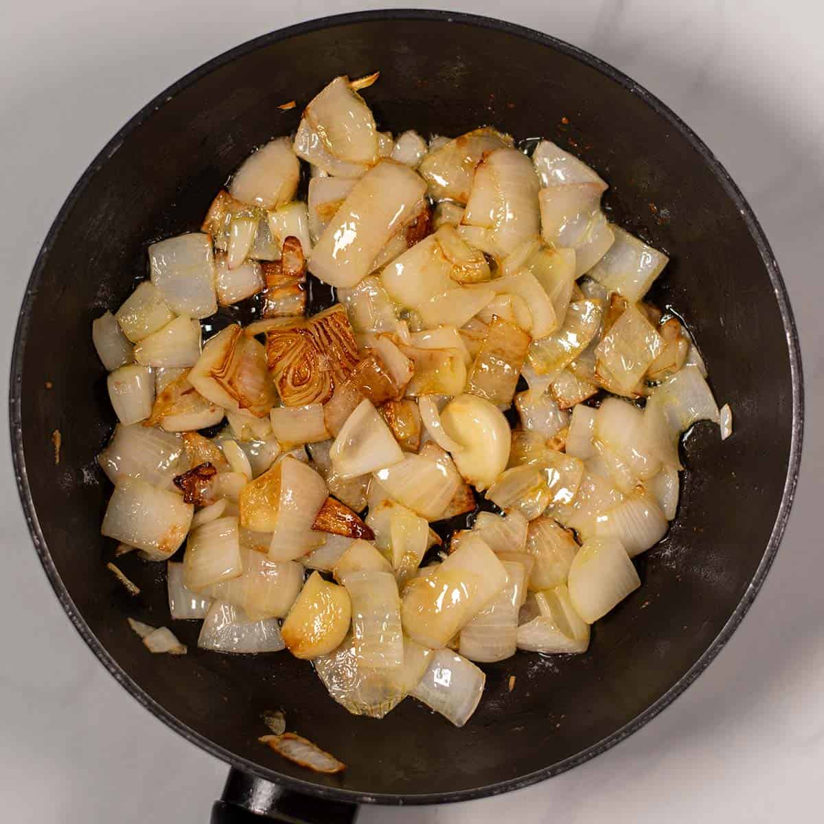 Onions and garlic cloves are roasted in a pan.
