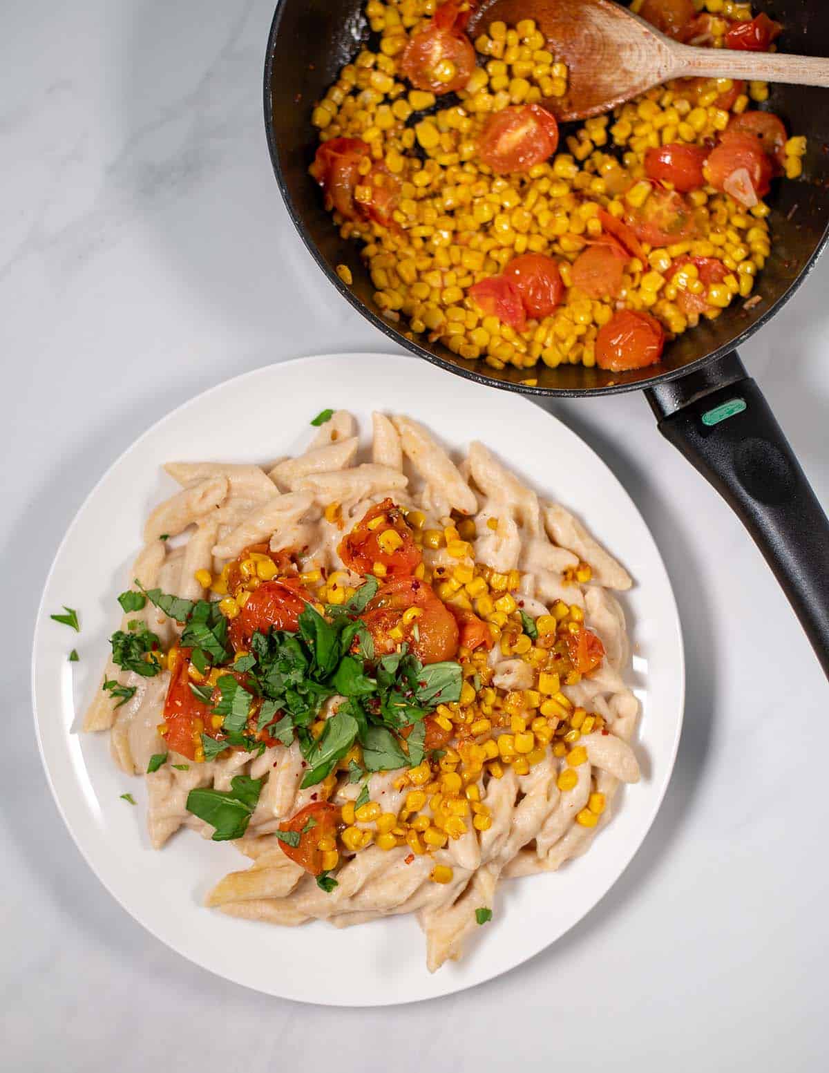 Serving of Corn Pasta on a plate with sauce pan in the background.
