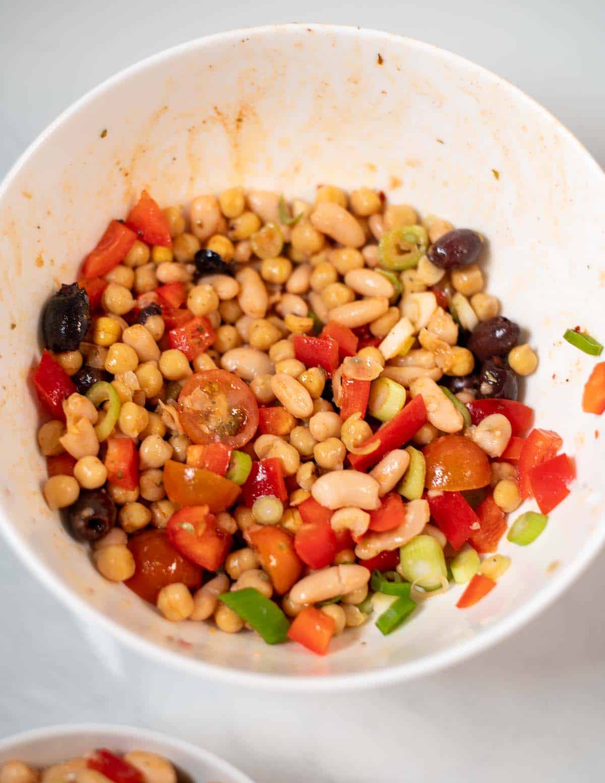 A large serving bowl with Dense Bean Salad.