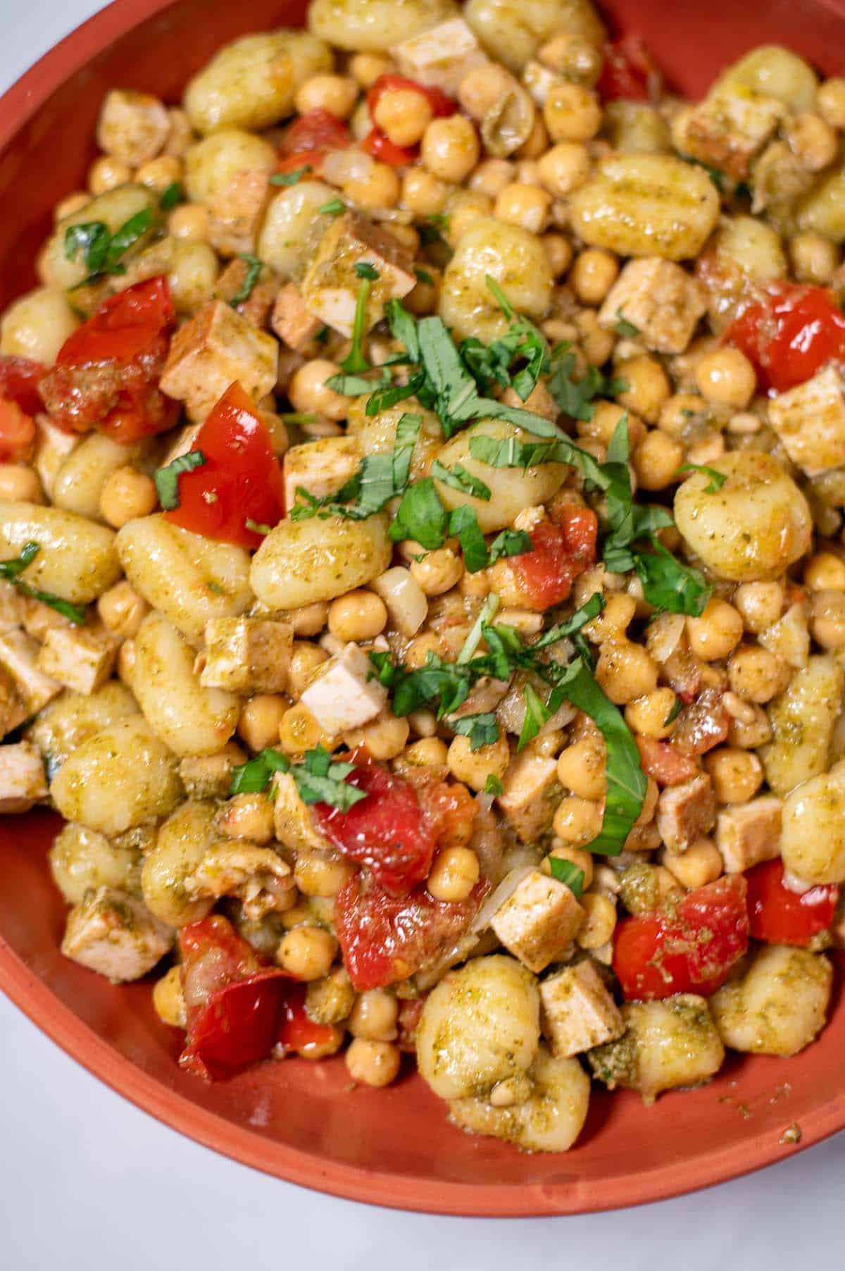 Fresh basil is used to garnish Pesto Gnocchi for serving.