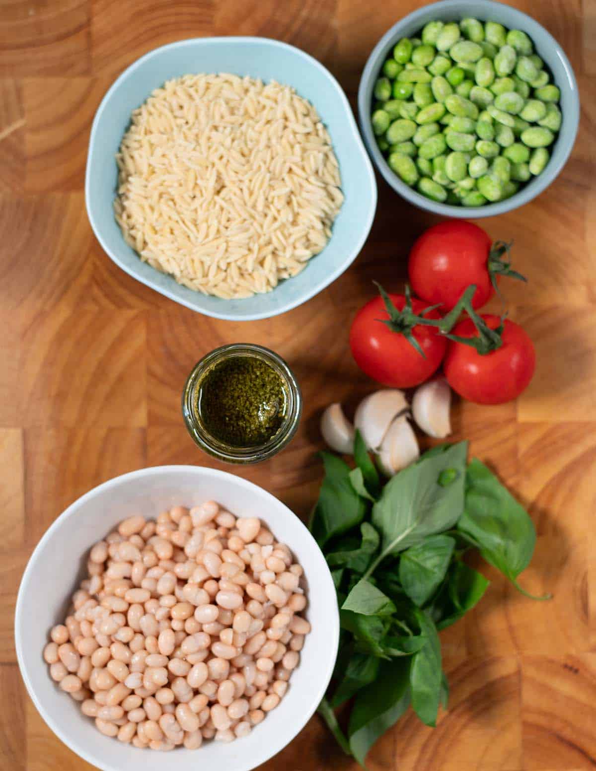 Ingredients needed to make Pesto Orzo collected on a baord.