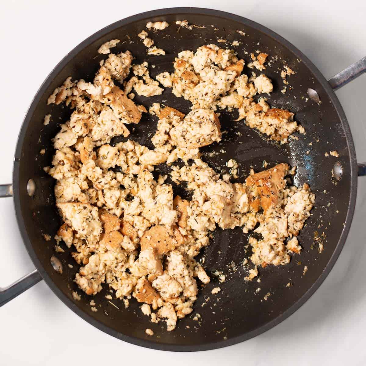 Crumbled seasoned tofu is fried in a pan.