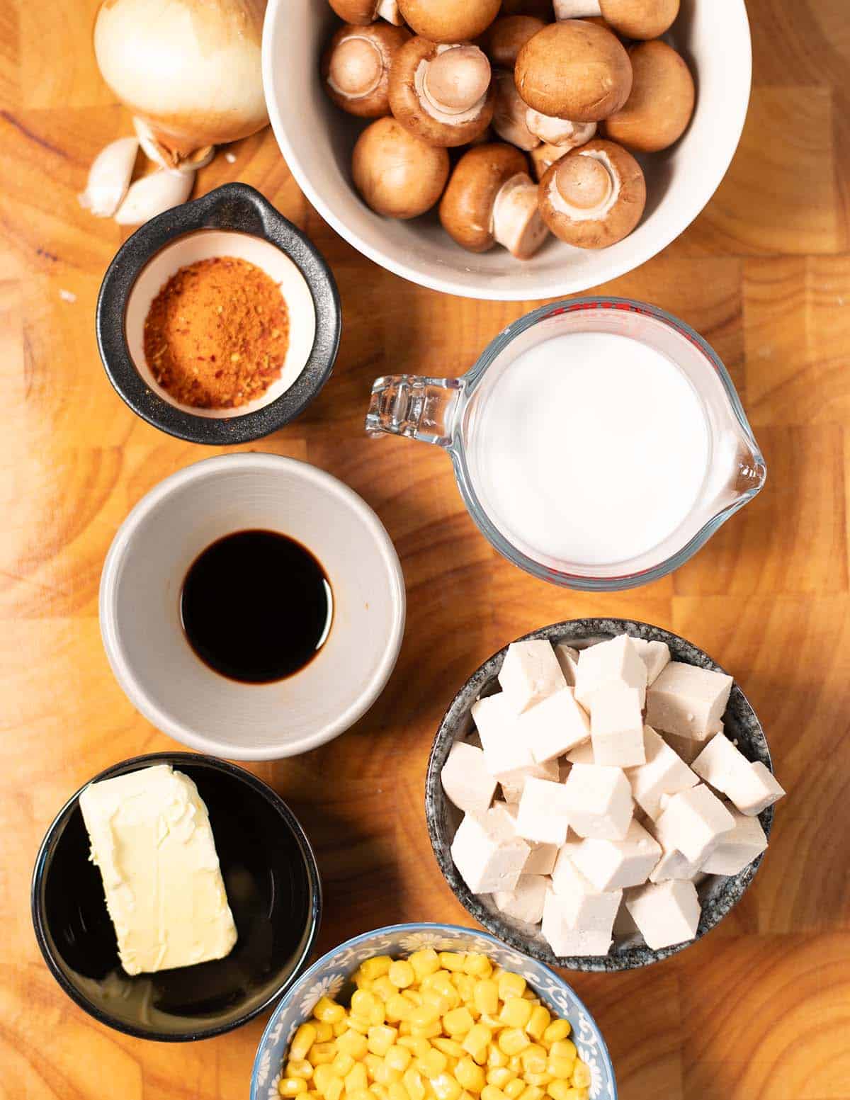 Ingredients needed to make Garlic Tofu are collected on a wooden board before preparation.
