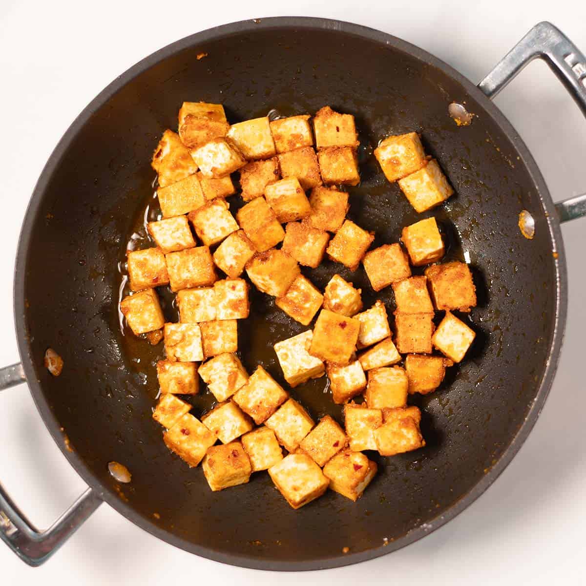 Crispy tofy cubes in a pan.