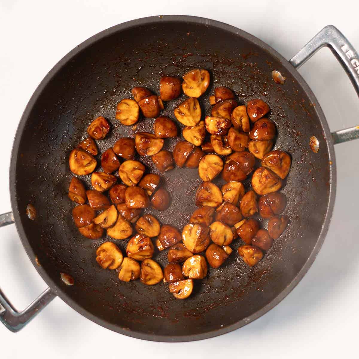 Sauteed mushrooms in soy sauce in a pan.