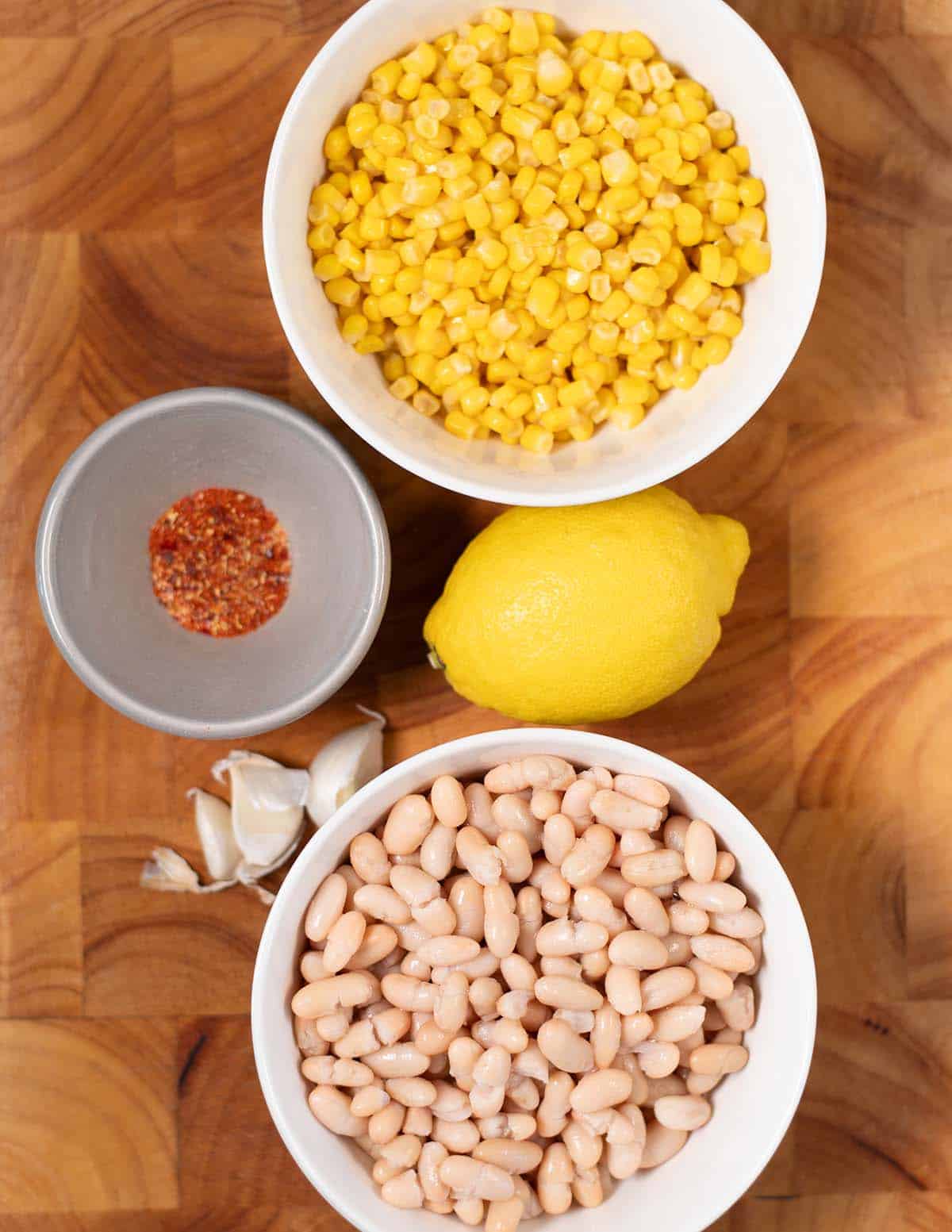 Ingredients needed to make High Protein Corn Dip are collected on a cutting board.
