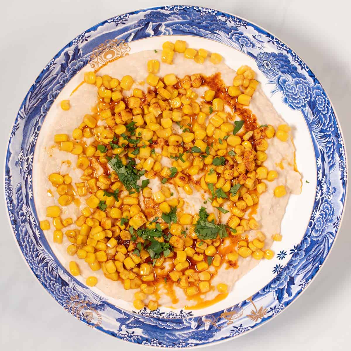 High Protein Corn Dip is served with roasted corn over the bean dip garnished with chili oil.