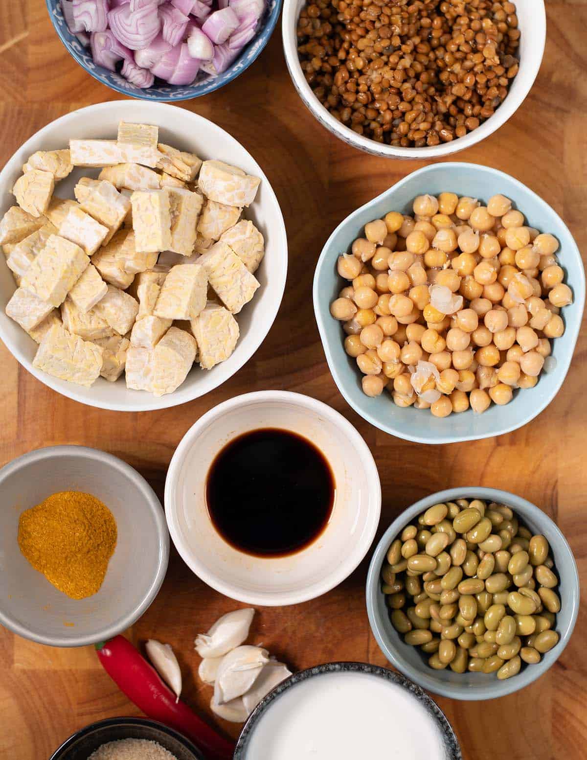 Ingredients needed to make High Protein Lentils collected on a wooden cutting board.