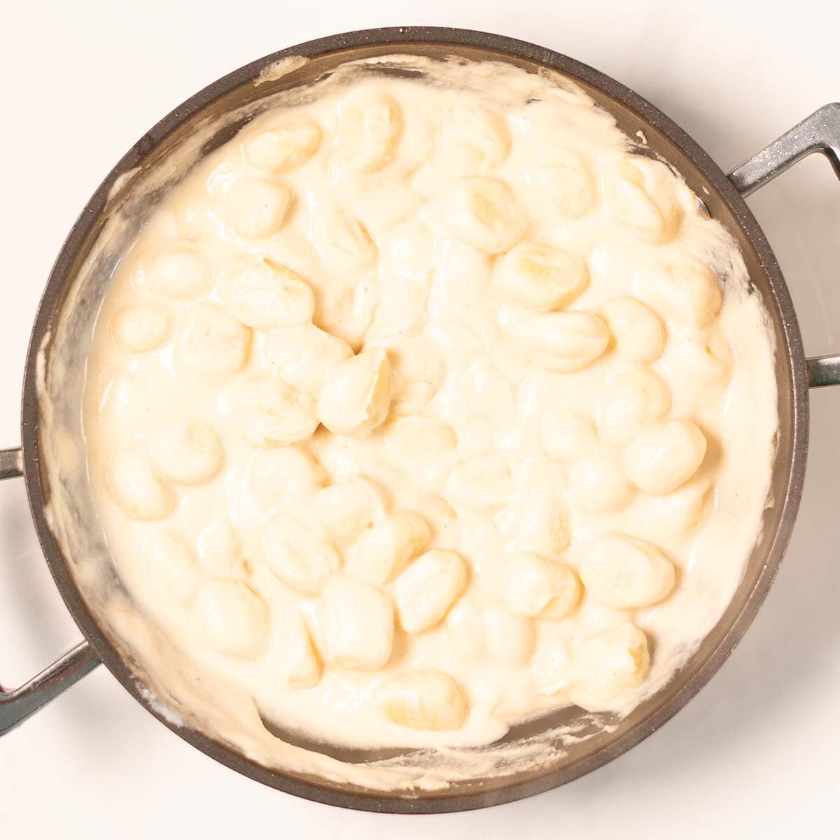 View of a pan with gnocchi in the cream bean sauce.