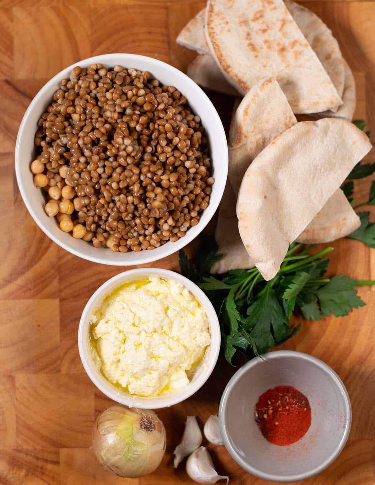 Ingredients needed to make Vegan Arayes are collected on a wooden board.