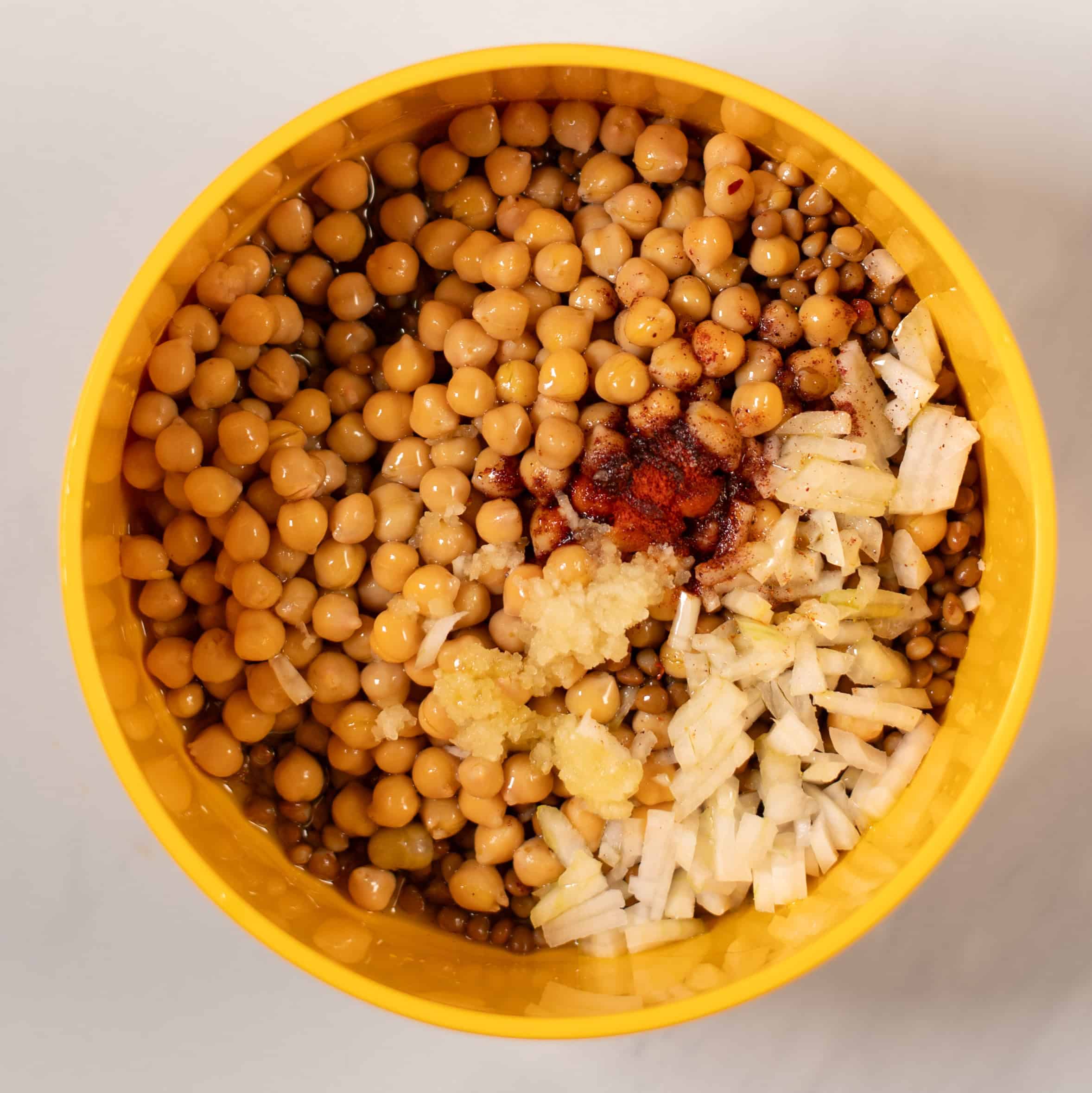 Chickpeas and lentils are given to a mixing bowl.