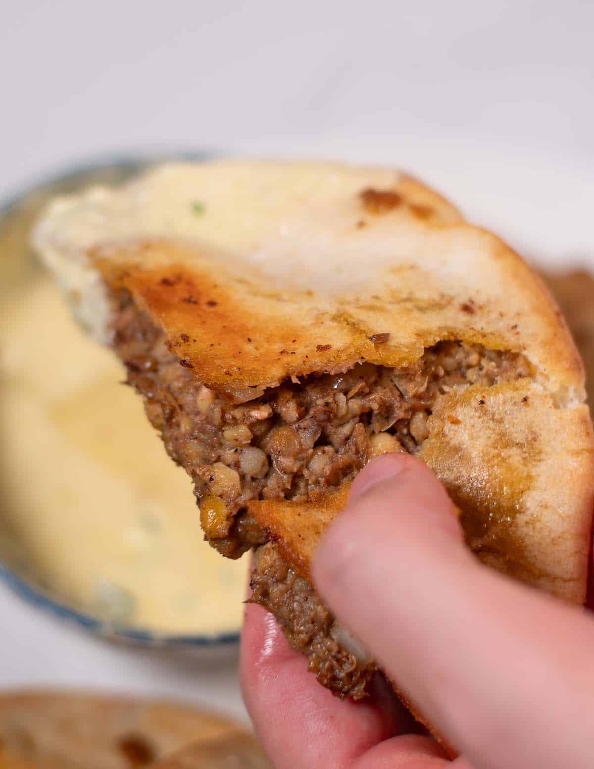 A vegan Arayes is dipped into sauce.