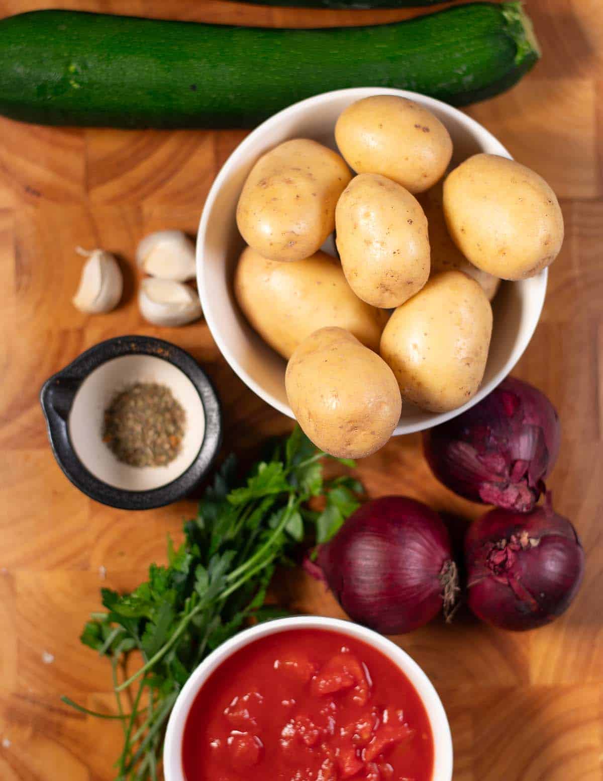 Ingredients needed to make Briam are collected before preparation on a cutting board.