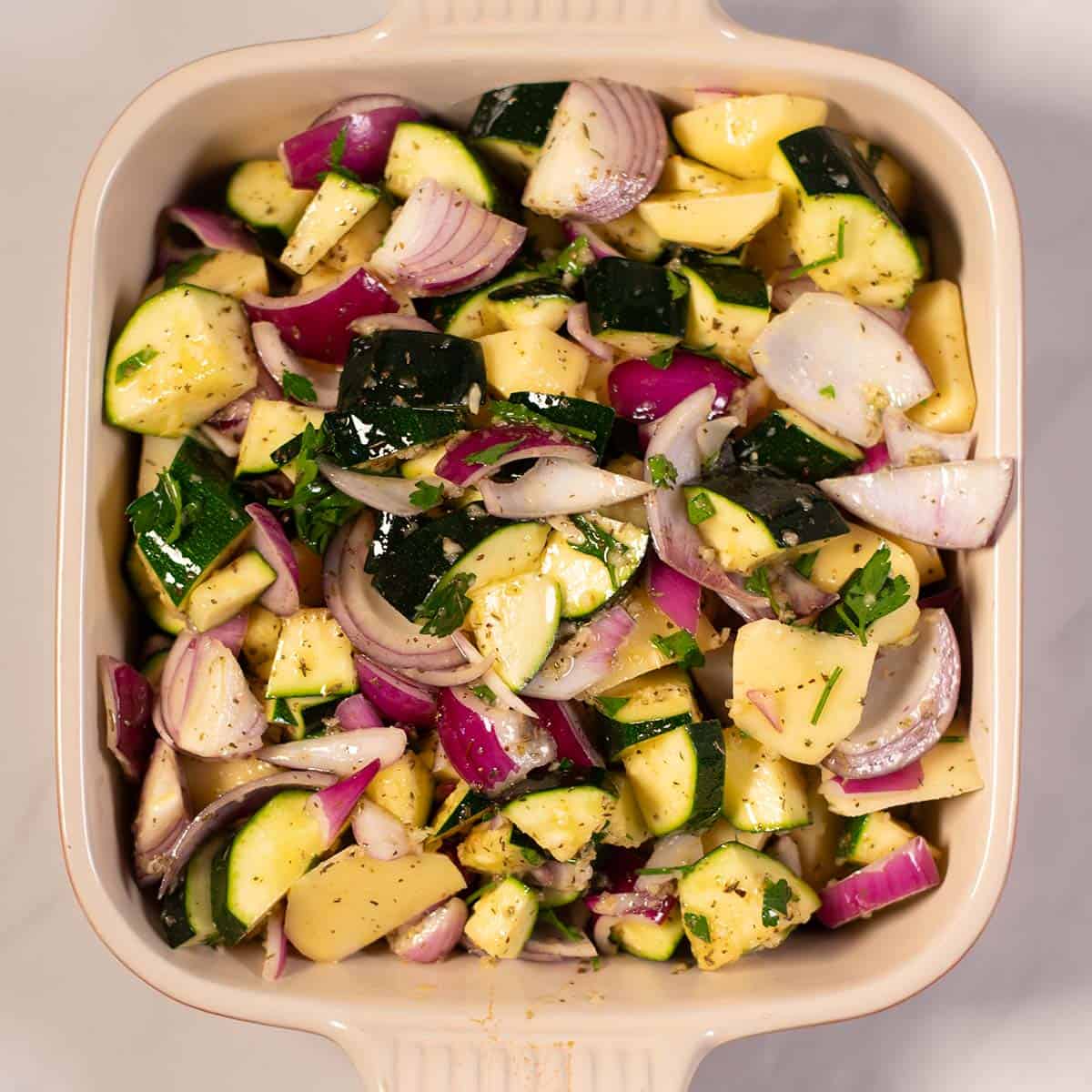 Seasoned vegetables are added to the baking dish.