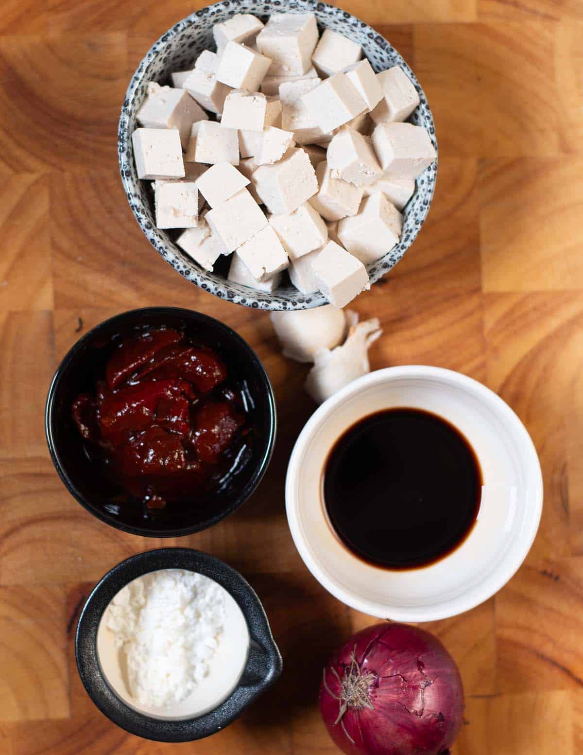 Ingredients needed to make Chipotle Tofu collected on a wooden board.