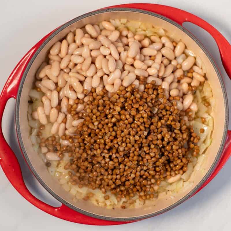 Onions, beans, and lentils in a large pan.