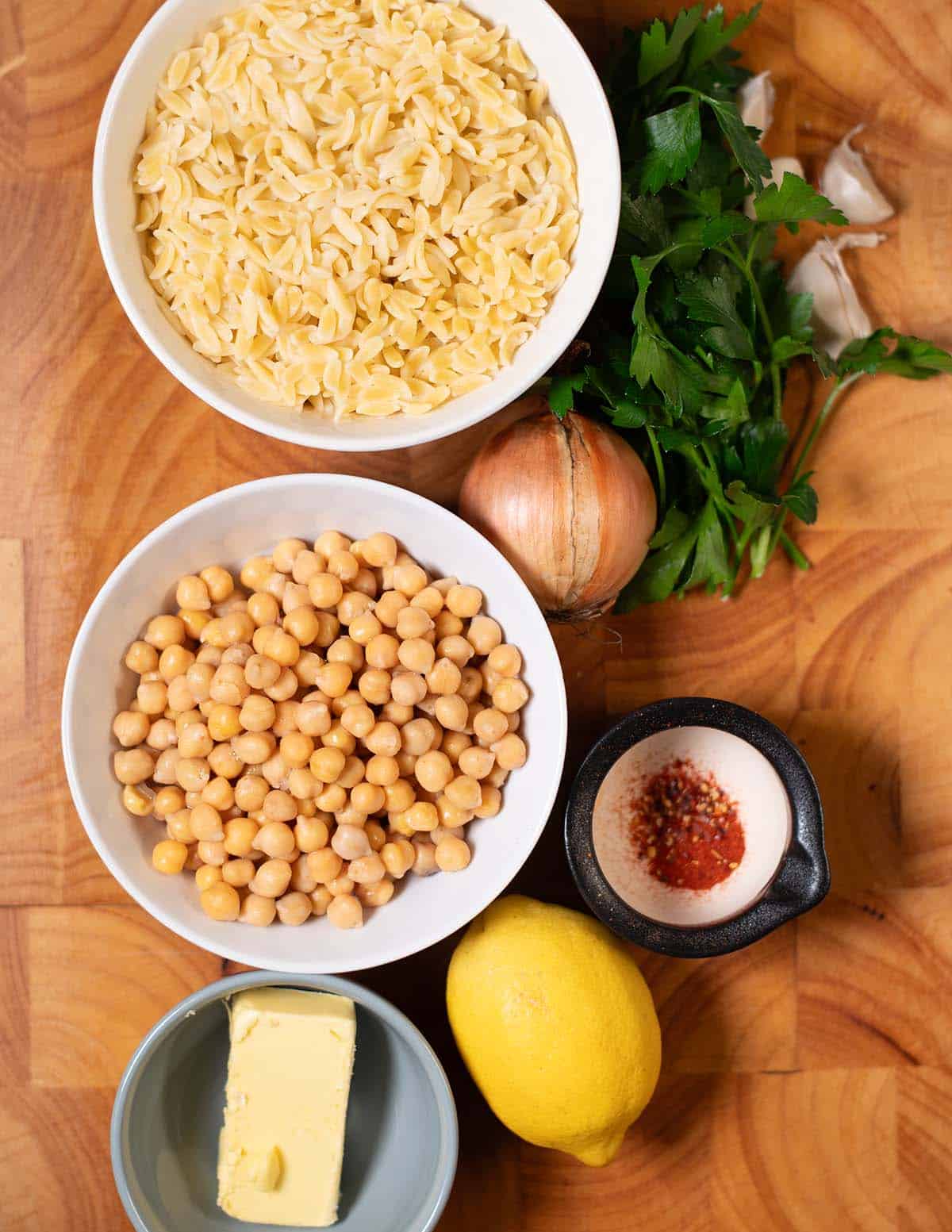 Ingredients needed to make Lemon Butter Orzo collected on a wooden board.