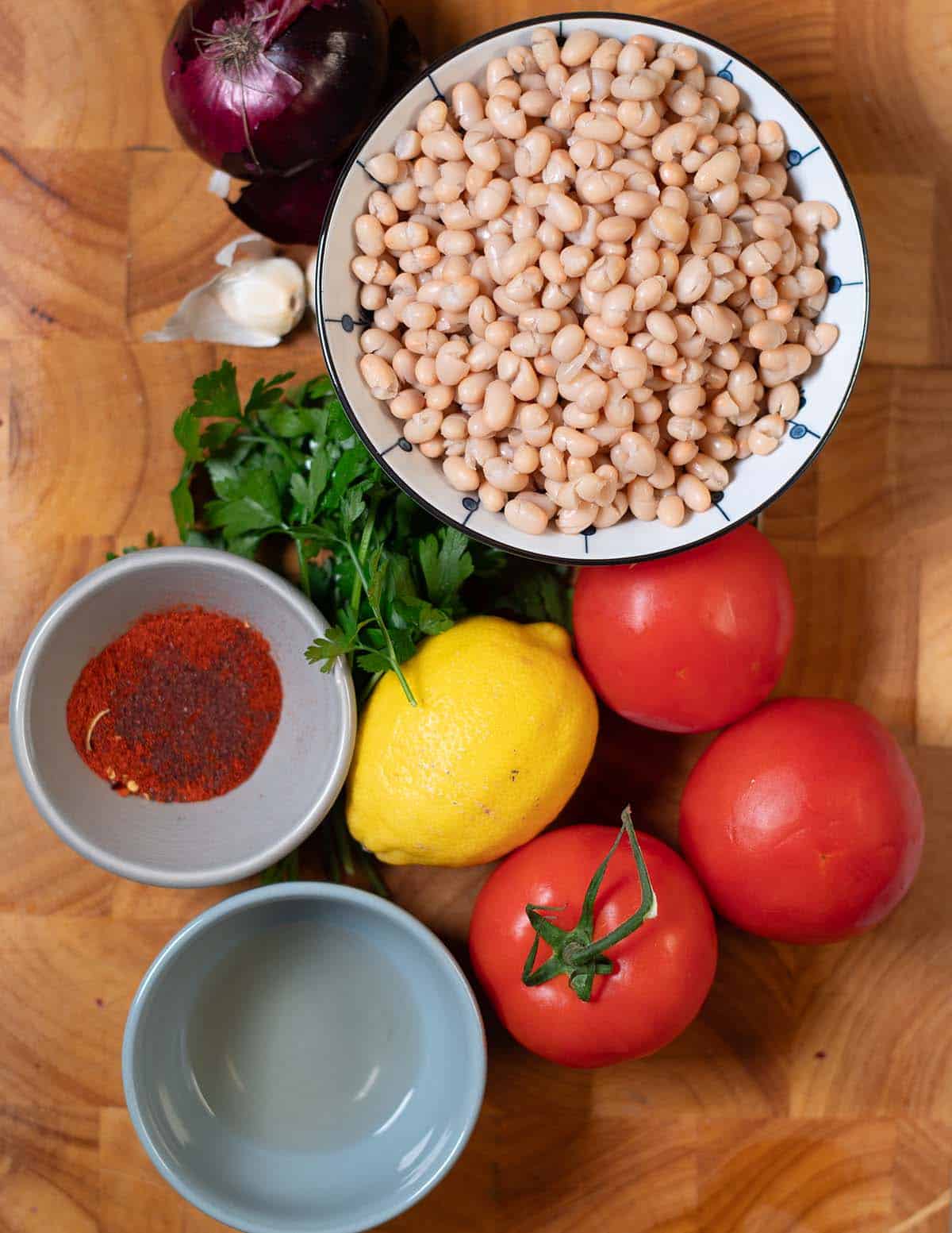 Ingredients needed to make Piyaz on a wooden cutting board.