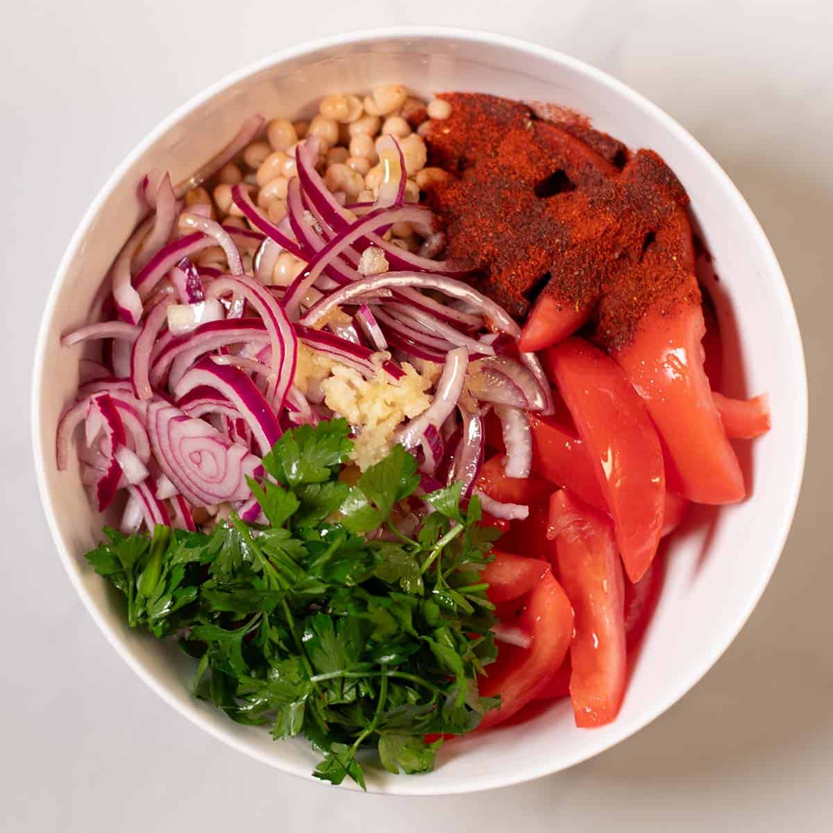 All ingredients for the Turkish White Bean Salad are given into a mixing bowl.