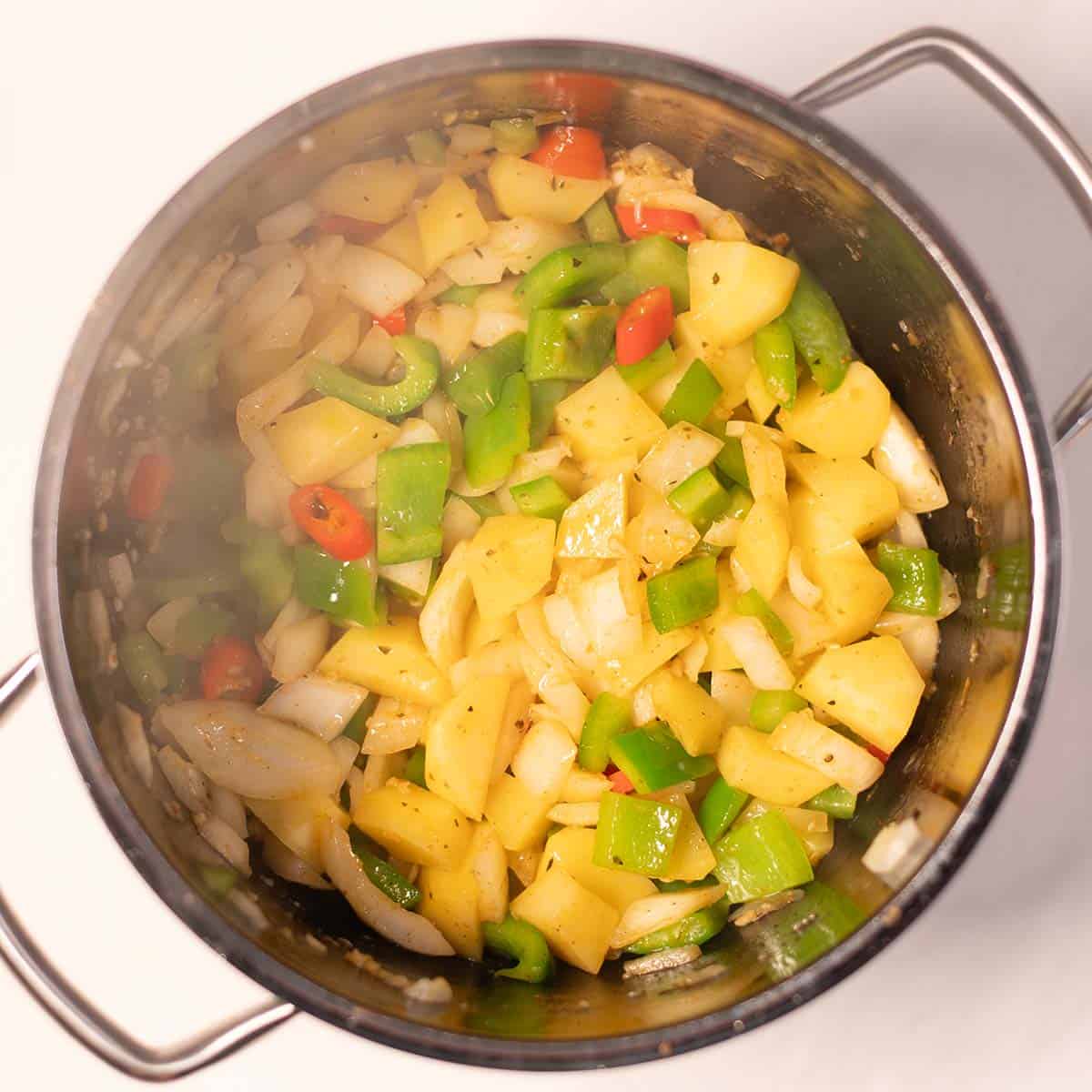 Potatoes and vegetables are fried in a large pot.