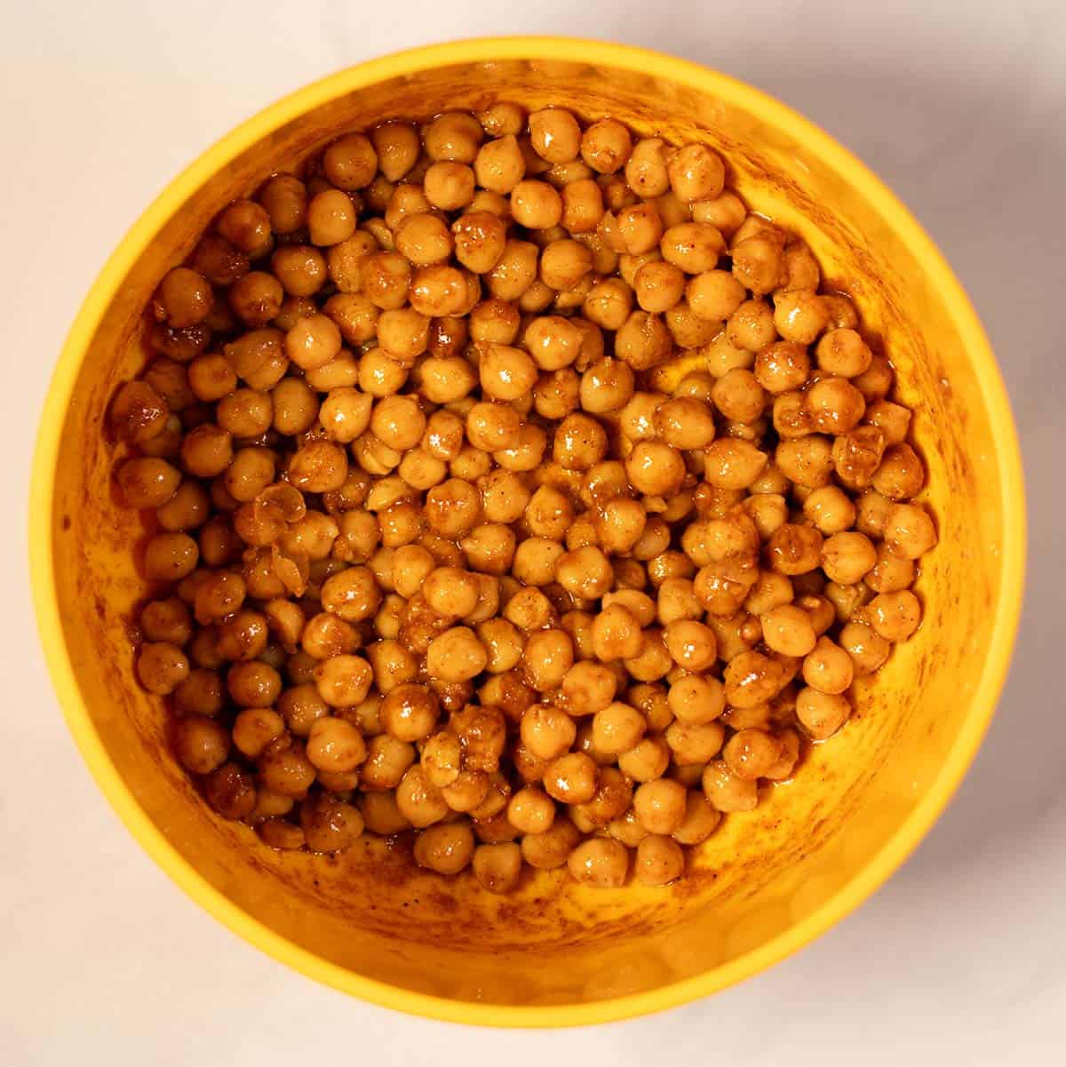 Cooked chickpeas in a yellow bowl, ready for use in chickpea shawarma bowls.