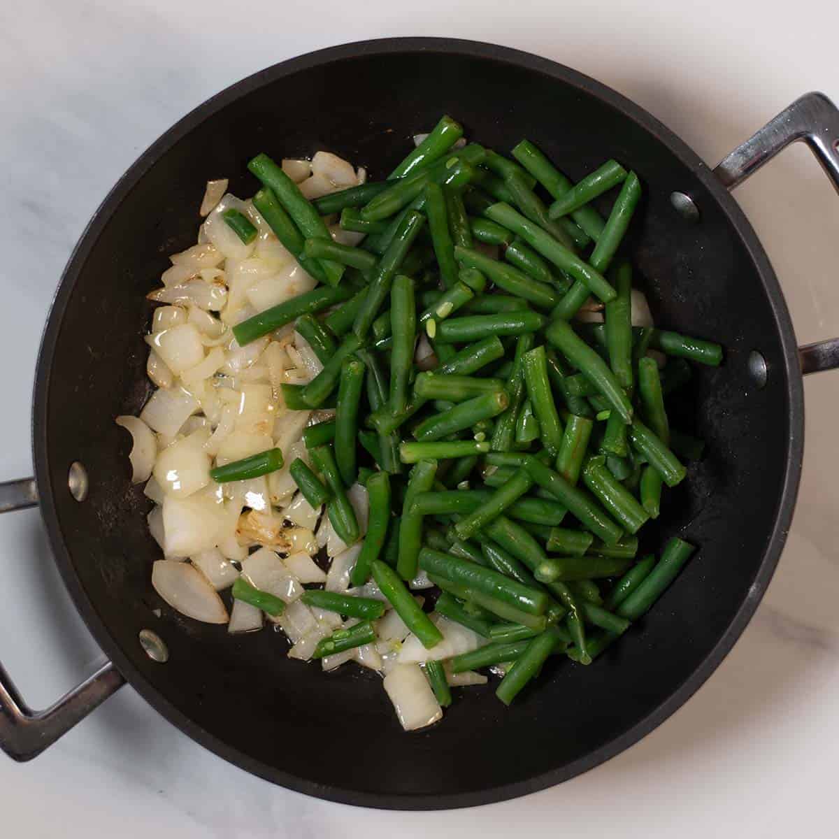 Green beans and onions cooking in a skillet for a healthy recipe.