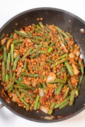 Green beans and lentils stir-fry in a black skillet for a high-protein meal.