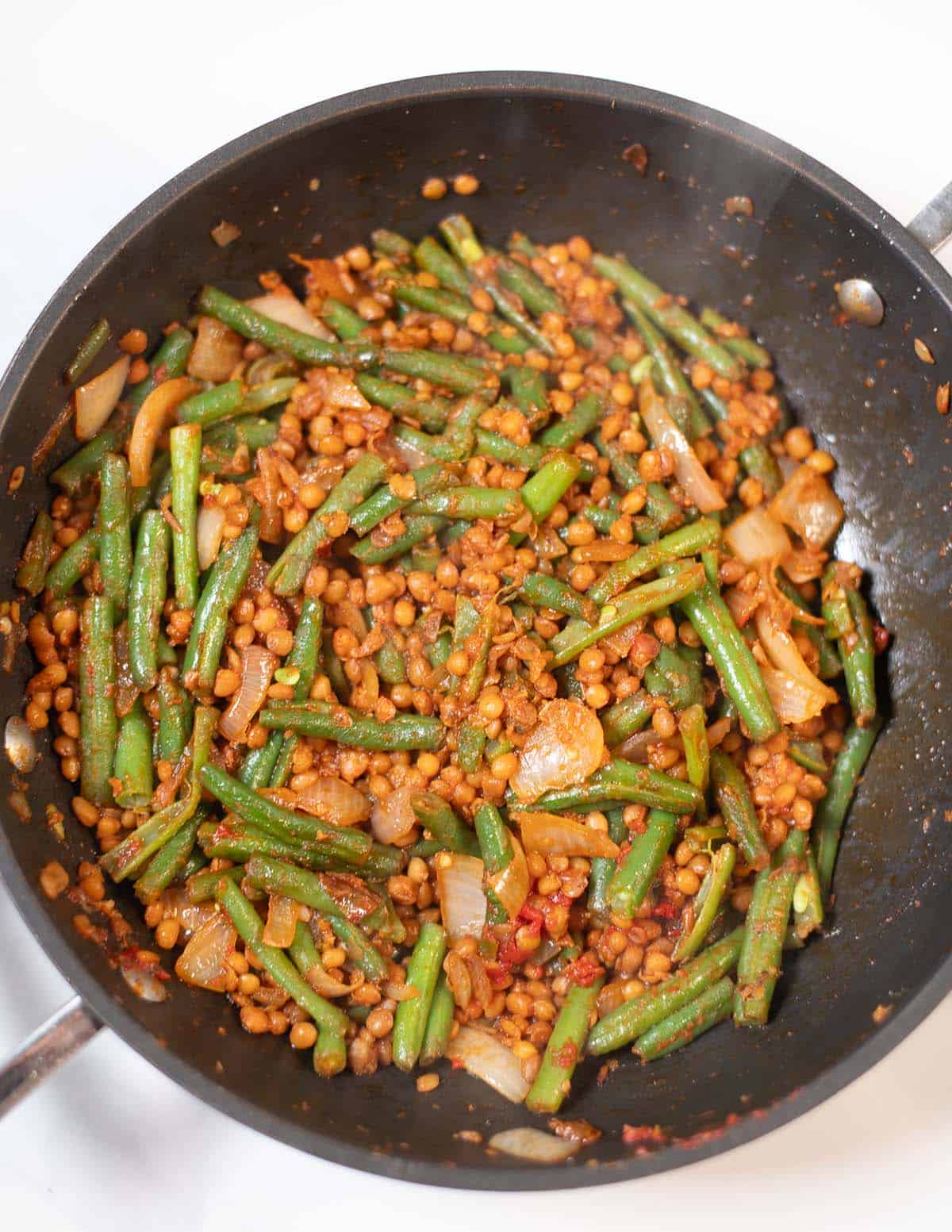 Green beans and lentils stir-fry in a black skillet for a high-protein meal.