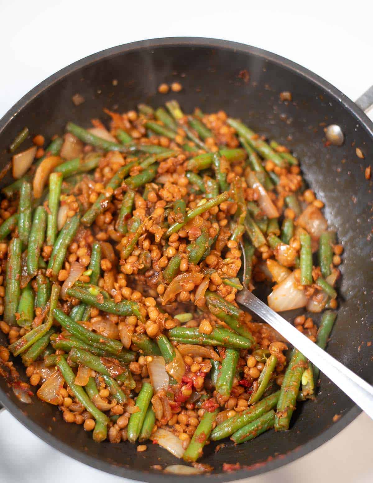 Green beans and lentils stir-fry in a skillet, ready to serve.