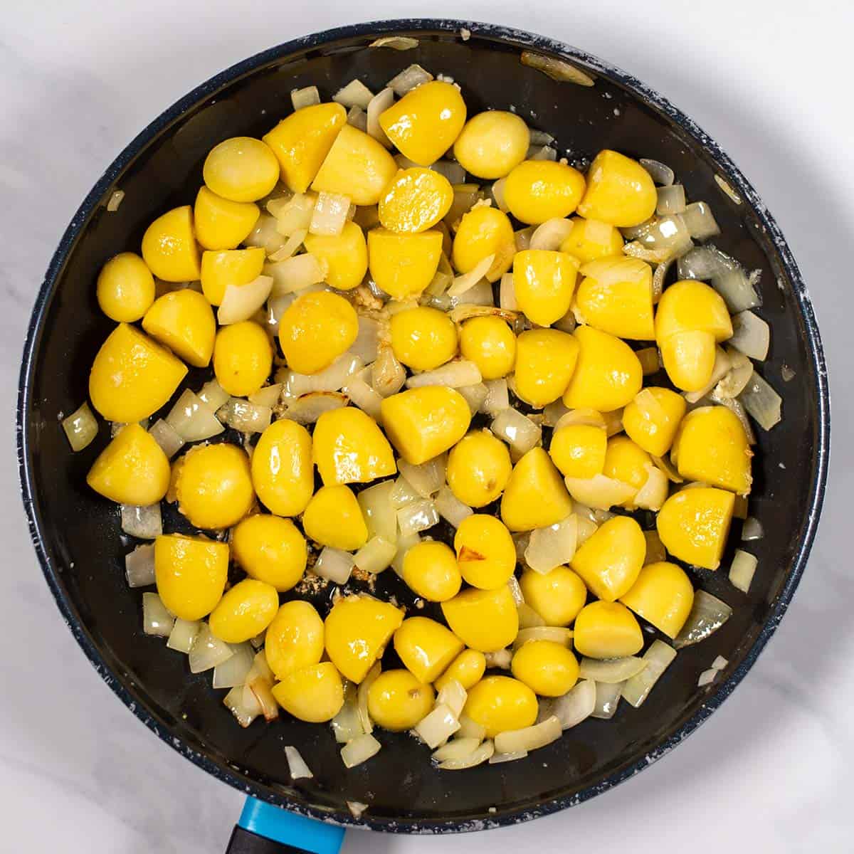 Yellow potatoes and onions cooking in a skillet for a high-protein dish.