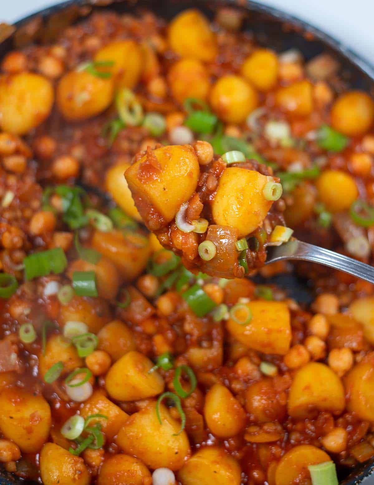 Hearty dirty potatoes with green onions in a skillet, ready to serve.
