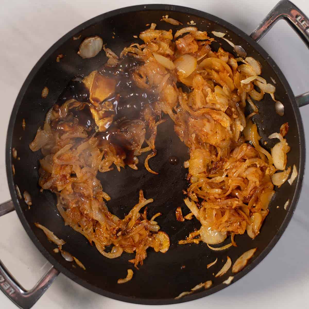 Sautéed onions and potatoes in a black skillet with caramelized edges.