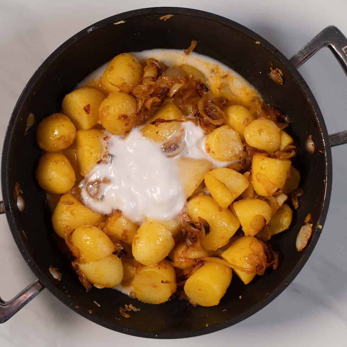 Creamy potatoes with caramelized onions in a skillet.